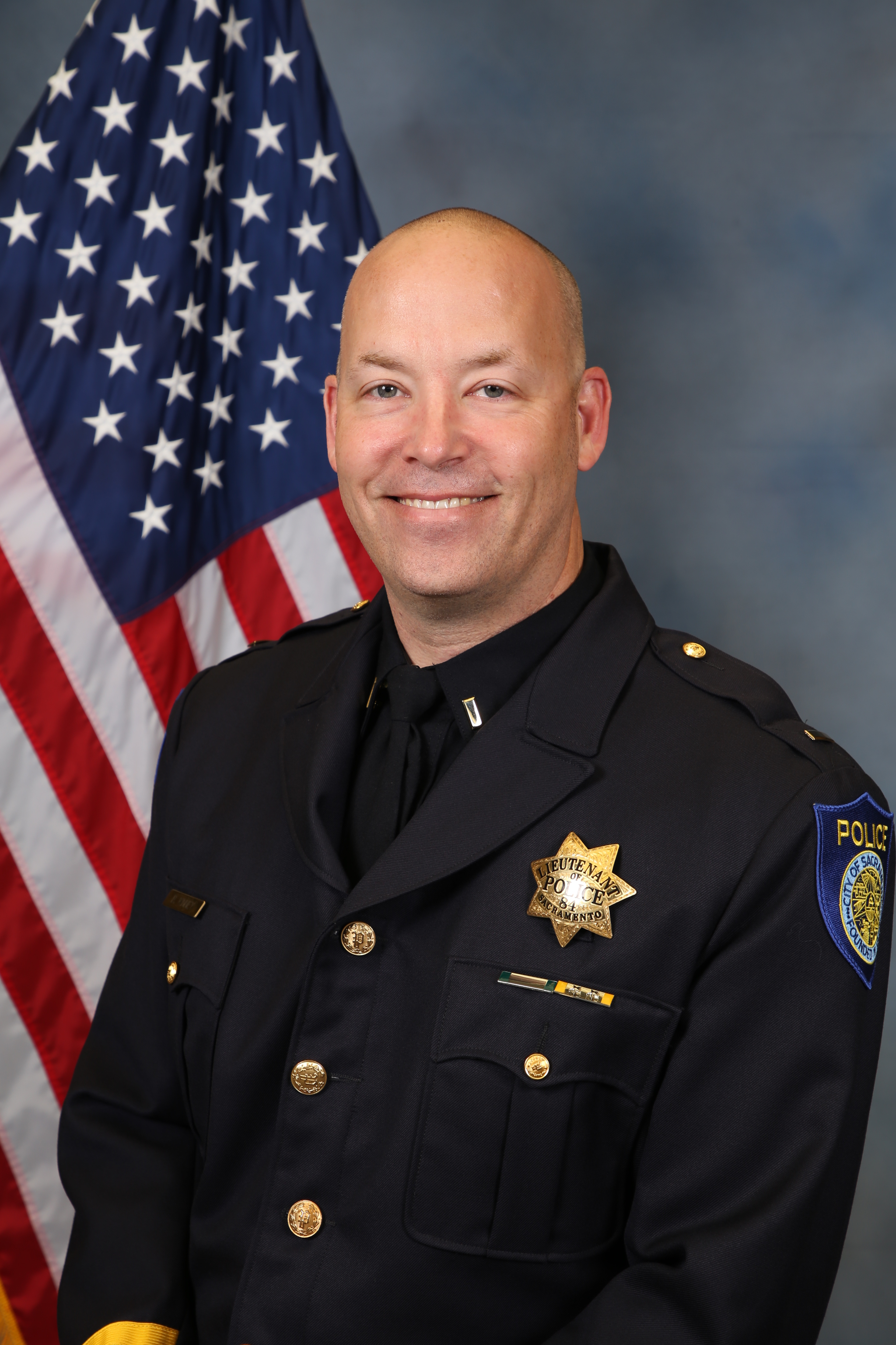 Photo of Brian Kinney in uniform in front of the American flag.