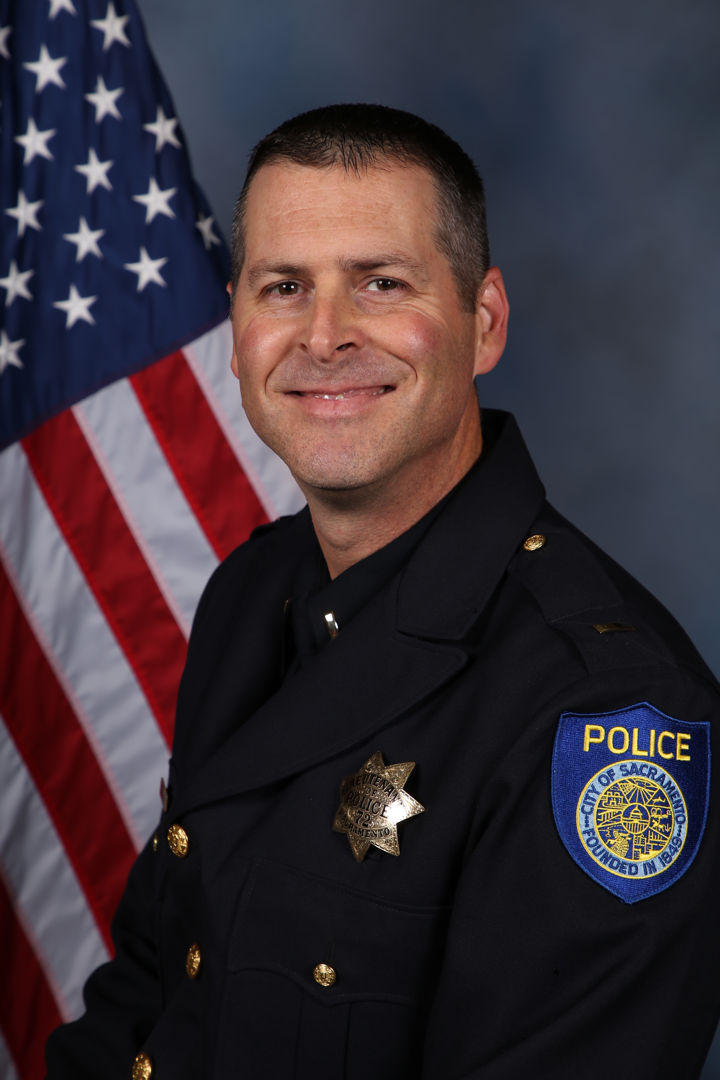 Photo of Gerald Landberg in uniform standing in front of the American flag.