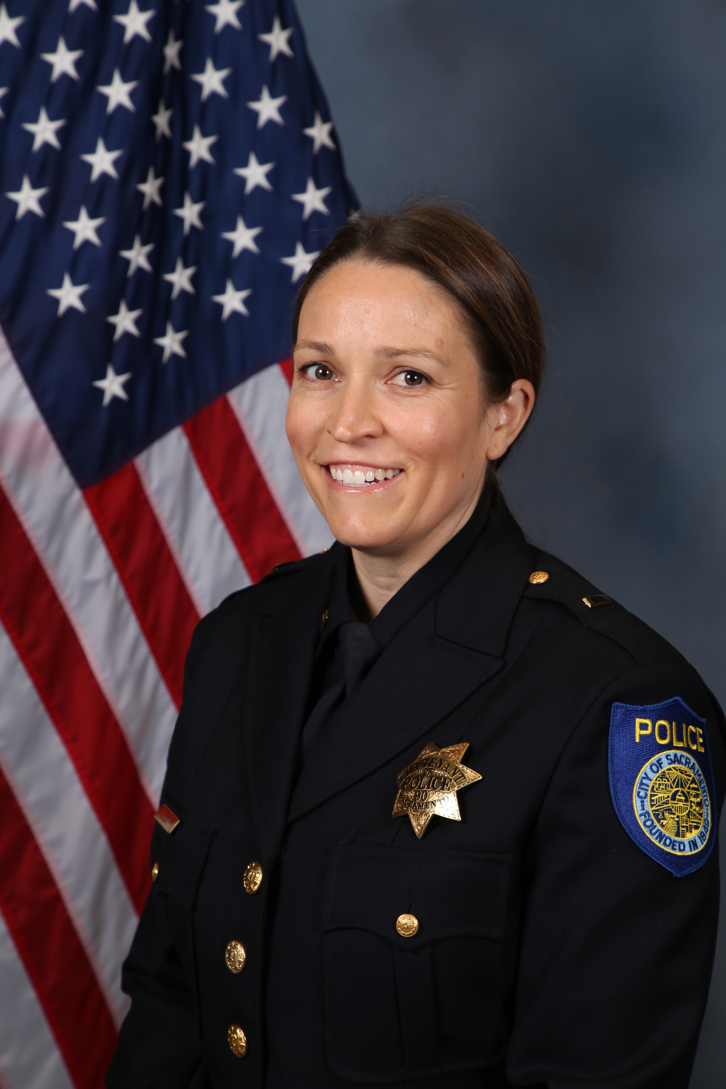 Photo of Jennifer Ligon in uniform standing in front of the American flag.