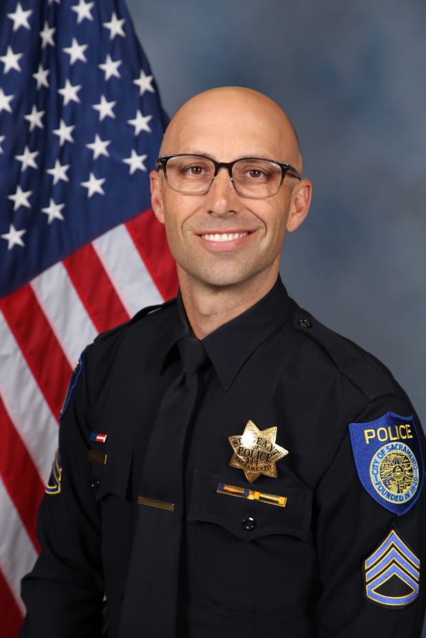 Photo of Lieutenant Matthew McPhail in uniform standing in front of the American flag.