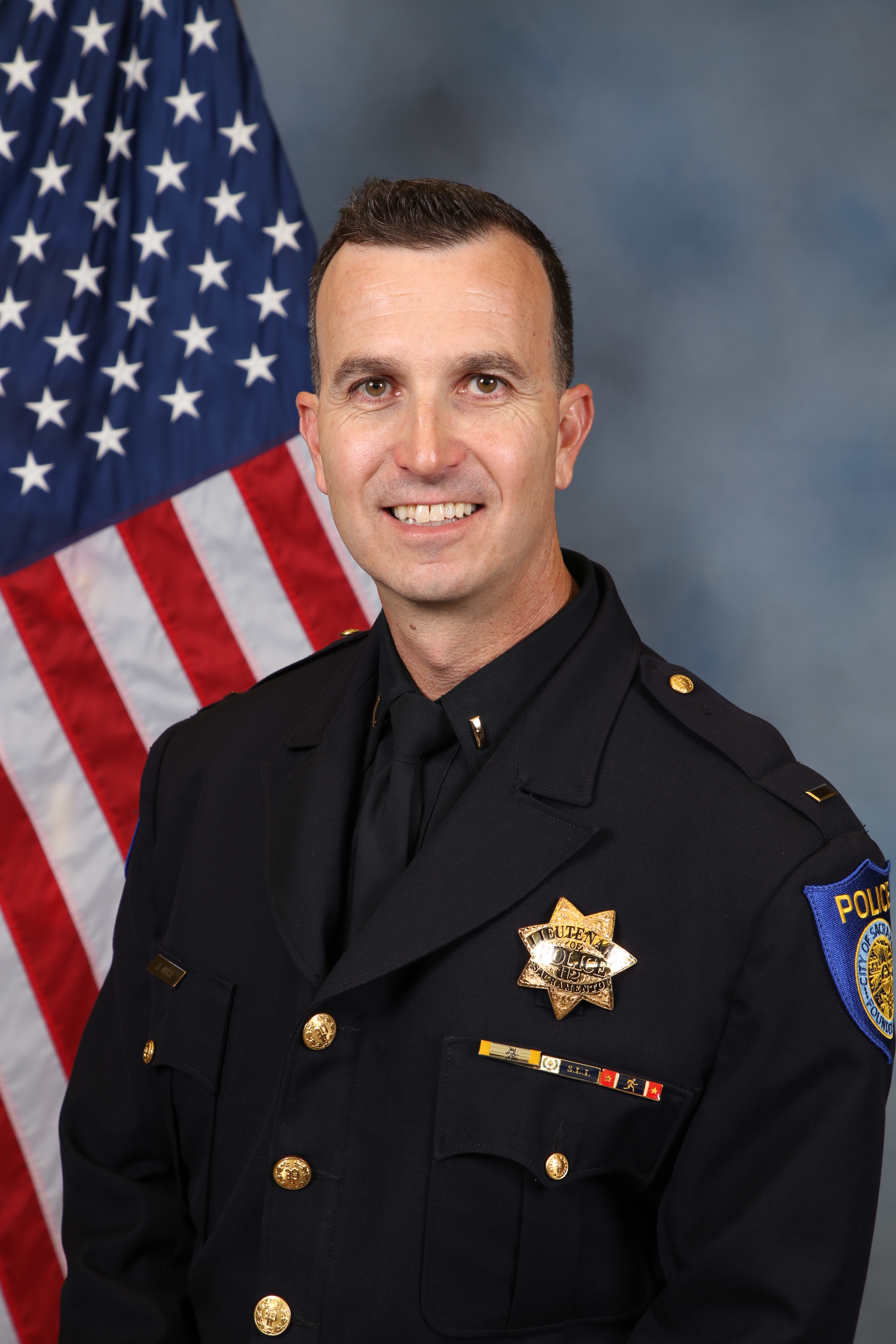 Photo of Doug Morse in uniform standing in front of the American flag.