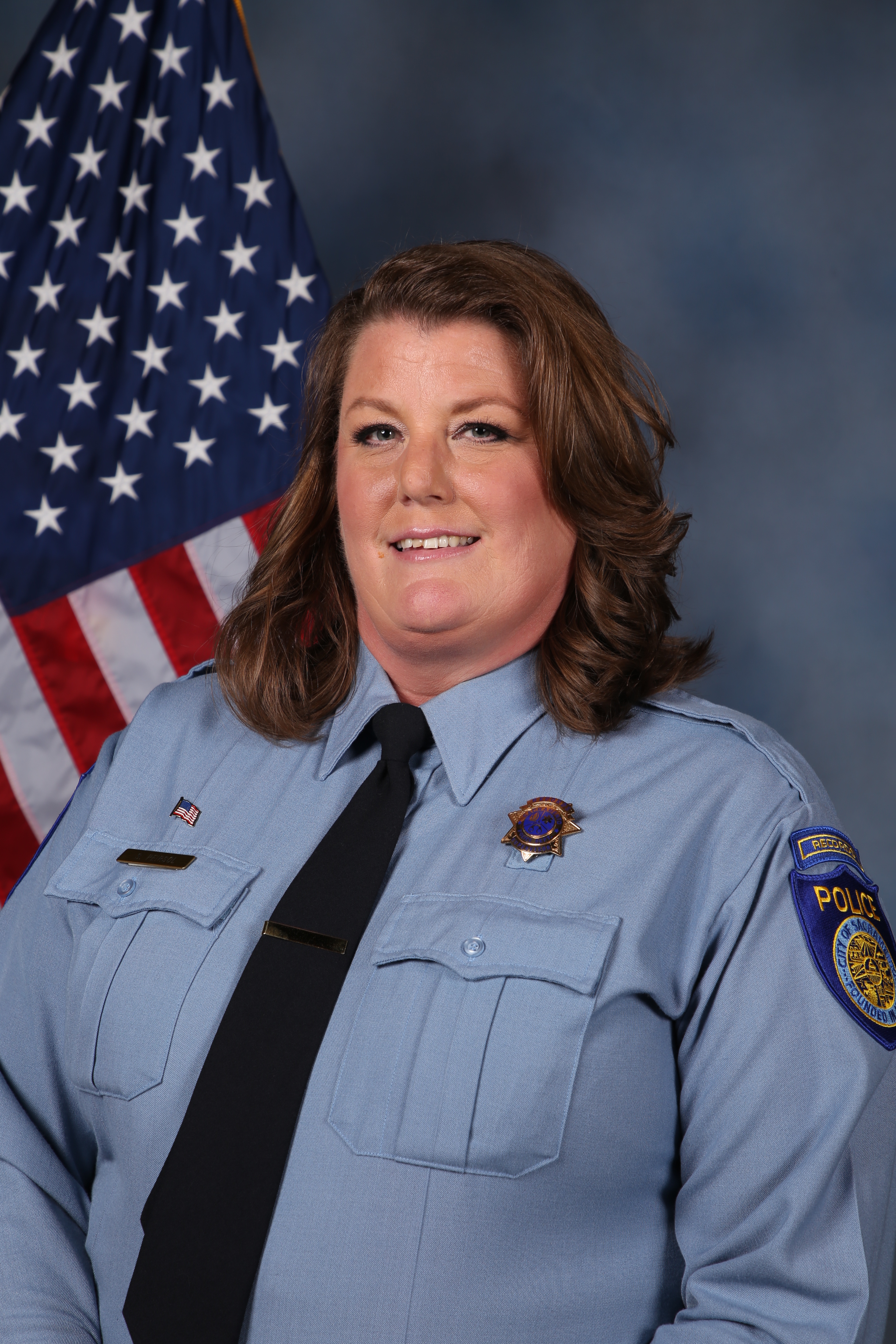 Photo of Senta Peirsol in uniform standing in front of the American flag.