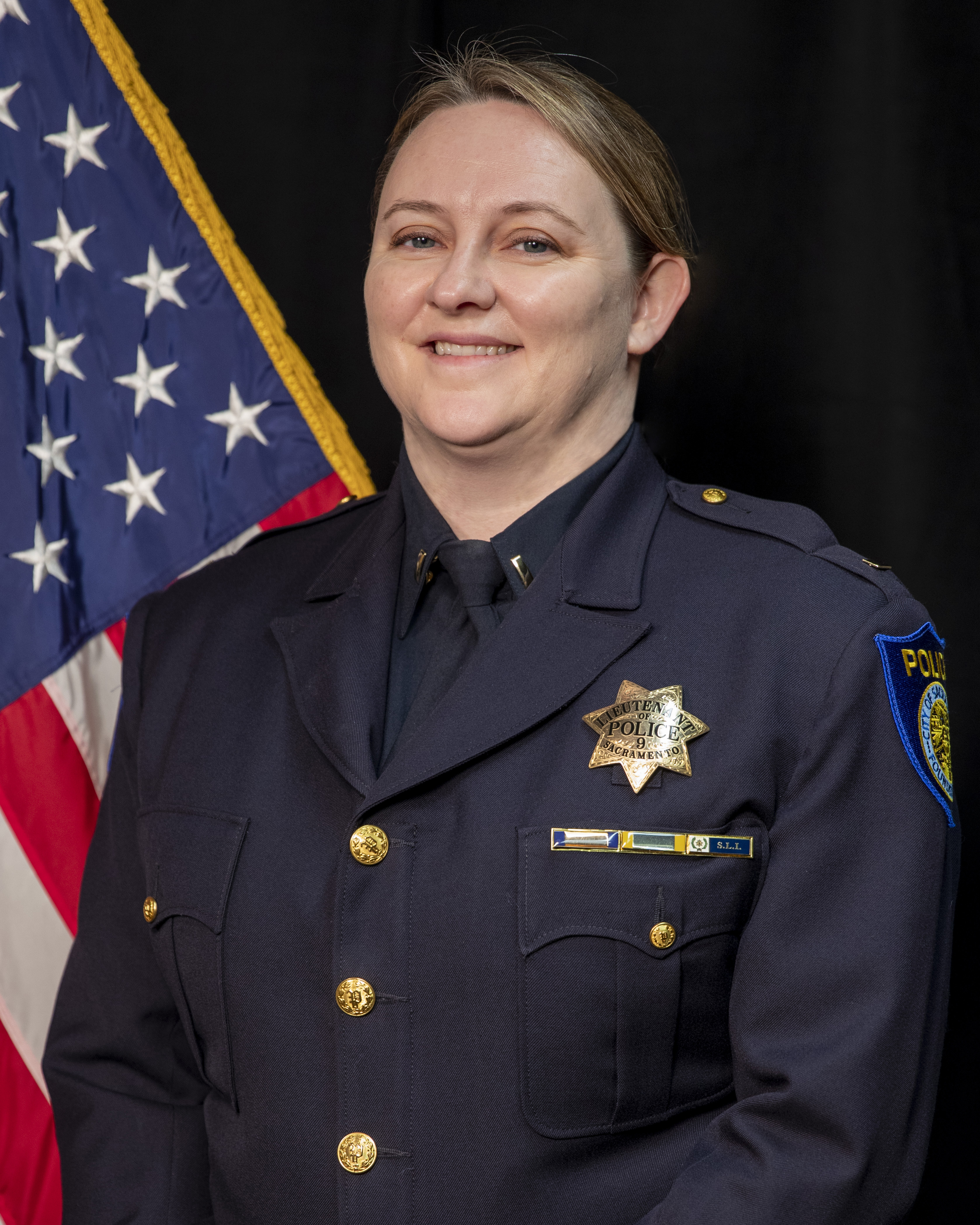 Photo of Kristine Morse in uniform standing in front of the American flag.