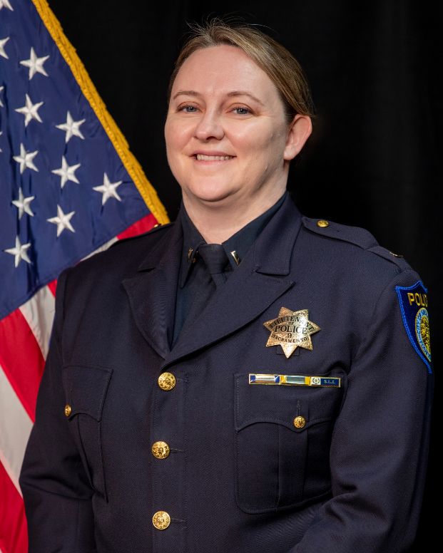 Photo of Kristine Morse in uniform standing in front of the American flag.