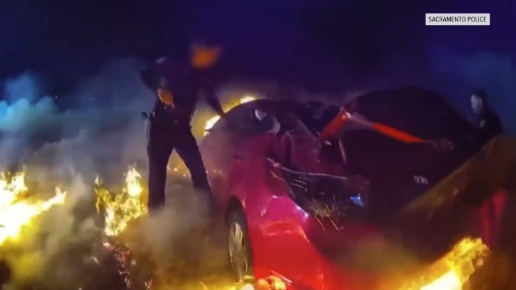 A photo of a sac pd officer in a field on fire next to a car on fire