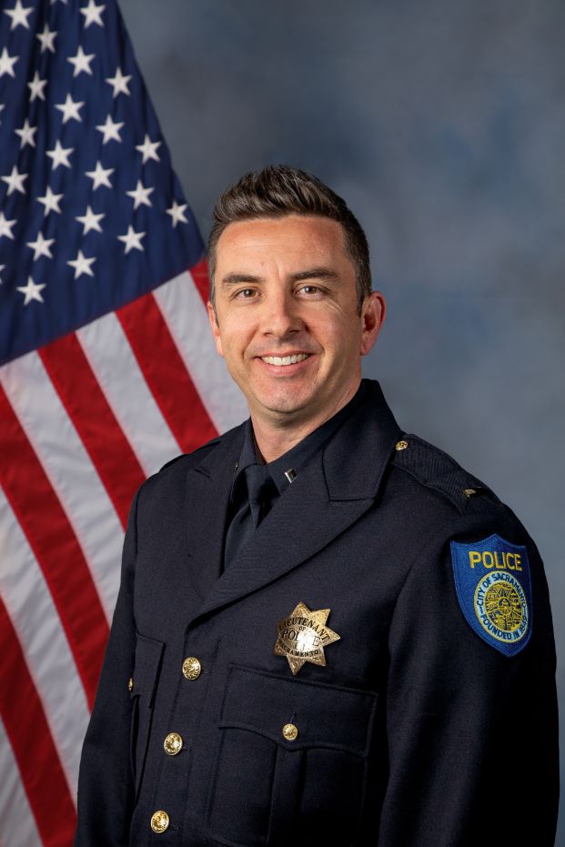 Photo of Lt. Justin Thompson in uniform with the american flag in the background.