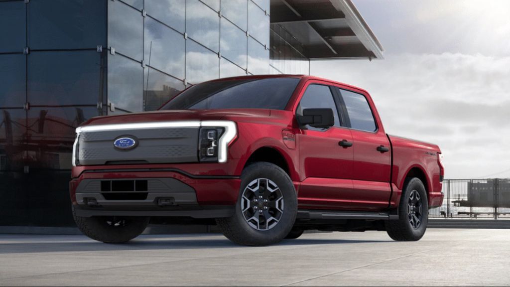 Red Ford F150, parked in front of an all glass building. 