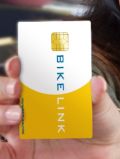 Image of a hand holding a white and yellow card with work Bike Link on the face of the card