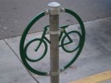 Image of green bike rack with bike emblem inside a circle and posted on a pole