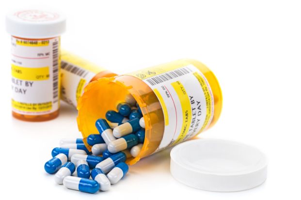 Prescription medicine bottles one is tipped over with blue capsules spilling out