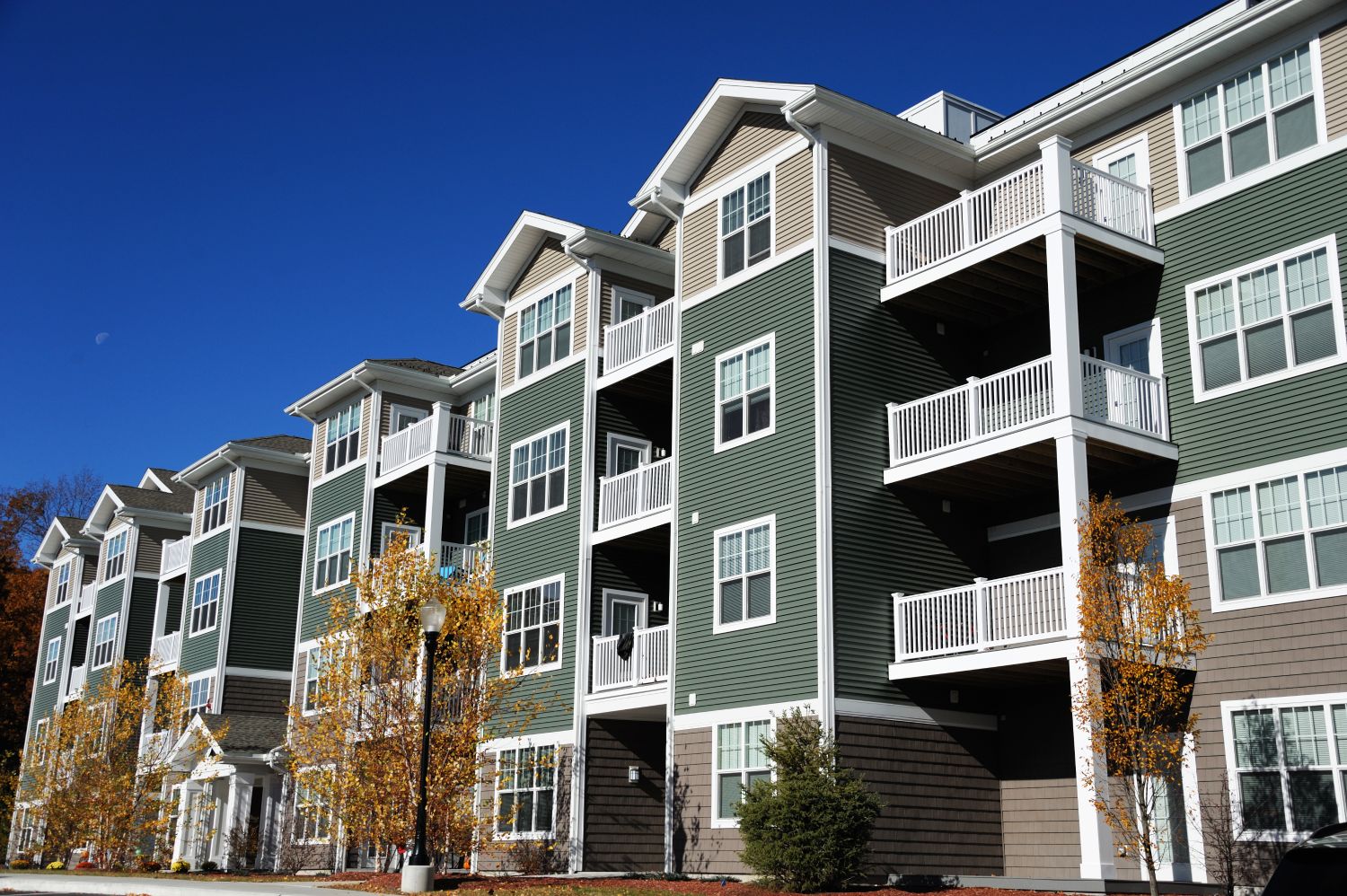 Sage green apartment building with beige top floor