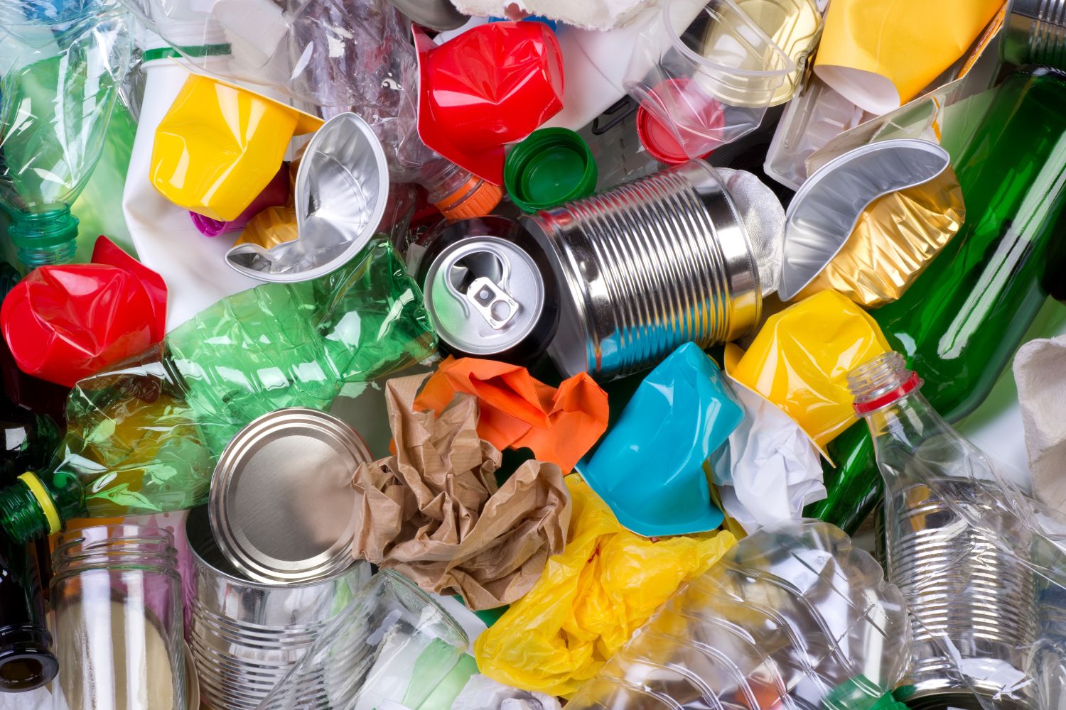 Glass bottles, metal containers, crumbled paper and hard plastics in a pile