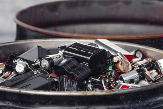 a pile of batteries, disposable and rechargeable, in a metal container