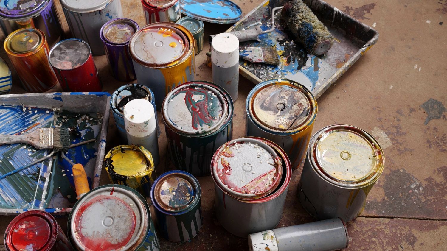 used paint cans and paint trays on a table 