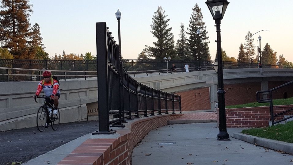 Pedestrians and cyclist using the Riverfront pathway at sunset.