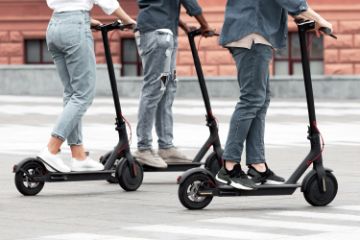 Cropped image of legs and feet of three people on motorized scooters